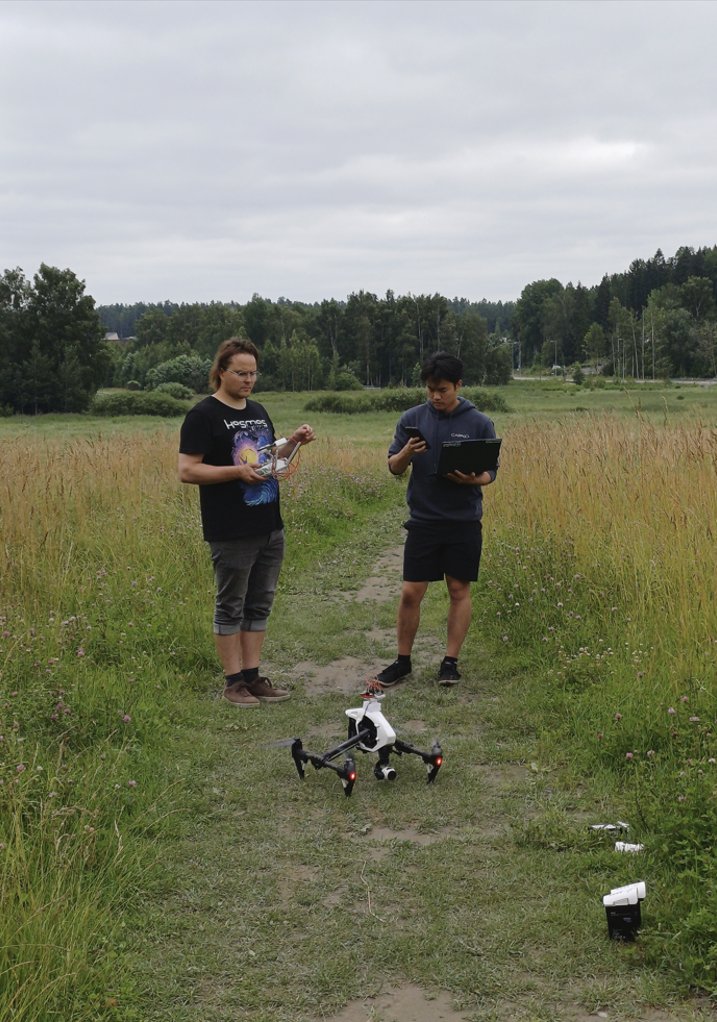 Two WeatherSens AI engineers preparing a sensor drone on a field track, laptop in hand.